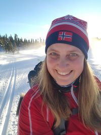 Portrait of young smiling woman wearing knit hat while skiing on snowy field