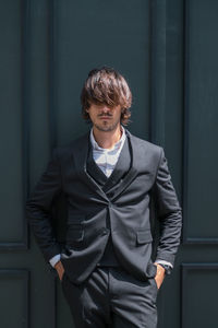 Portrait of young man standing against wall