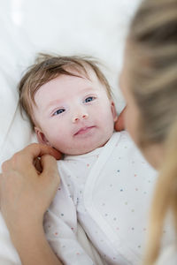 Cropped image of mother with toddler daughter lying on bed