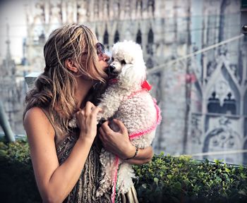 Woman kissing dog standing outdoors