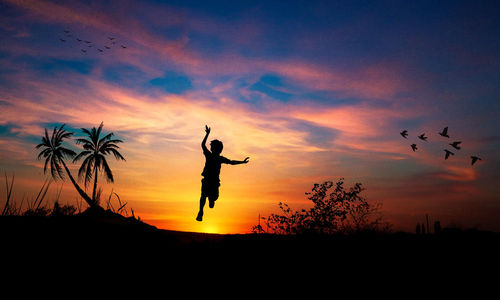 Silhouette boy jumping over field against romantic sky during sunset