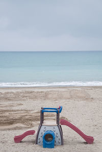 Deck chairs on beach against sky