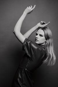 Portrait of young woman standing against black background