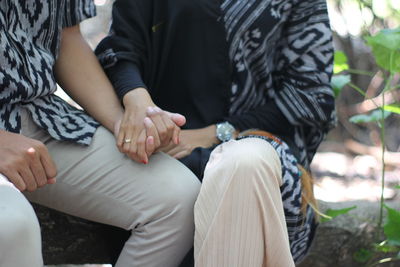 Midsection of couple sitting outdoors