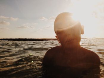 Rear view of shirtless man standing at beach against sky