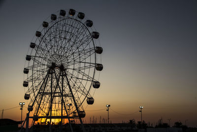 Low angle view of ferris wheel against sky at sunset