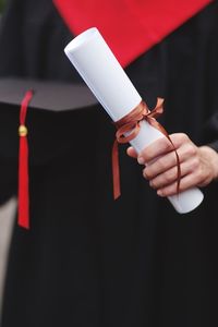 Midsection of male university student holding degree