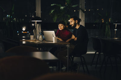 Businessman and businesswoman using laptop while working late night at office