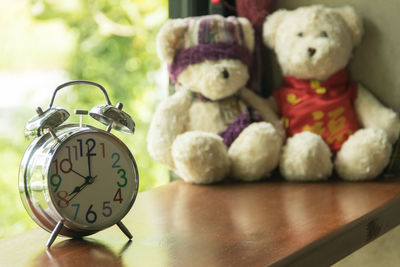 Close-up of alarm clock with teddy bears on wooden table