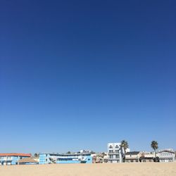 Buildings by beach against clear blue sky