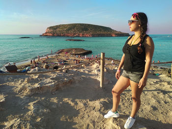 Young woman on beach by sea against sky