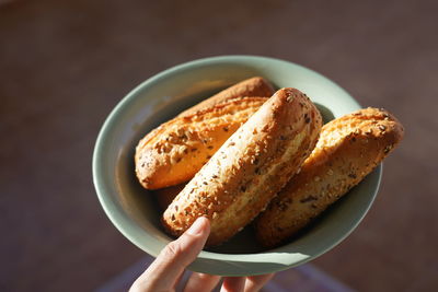 Close-up of hand holding plate with white baguette bread