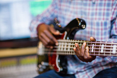 Midsection of man playing guitar