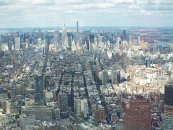 High angle view of city buildings against cloudy sky