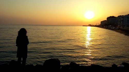 Silhouette woman standing at beach during sunset