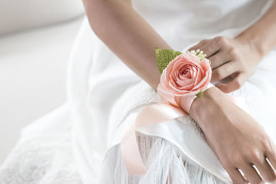 Midsection of bride with floral patterned bracelet sitting over against white background