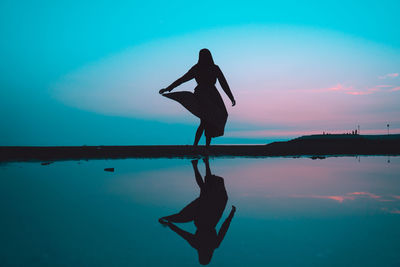 Silhouette woman standing by sea against sky during sunset