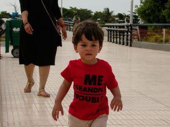 Low section of mother with cute son walking on footpath