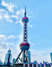 Communications tower in city against sky