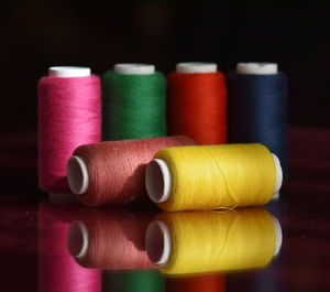 Close-up of multi colored thread spools on table against black background