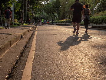 Rear view of people walking on street in city