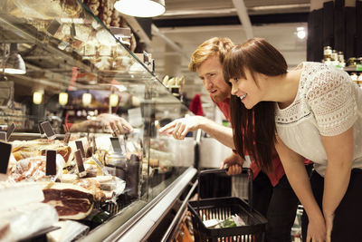 Young couple choosing fresh meat at supermarket