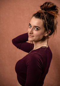 Portrait of smiling woman standing against wall