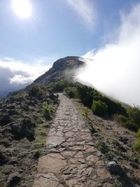 Footpath leading towards mountain against sky