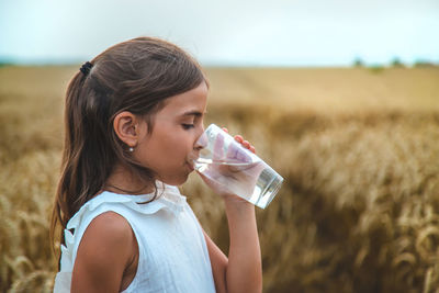 Cute girl drinking water on field