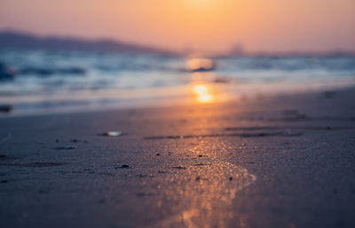 Surface level of beach against sky during sunset