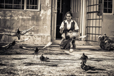 Full length of young woman feeding birds