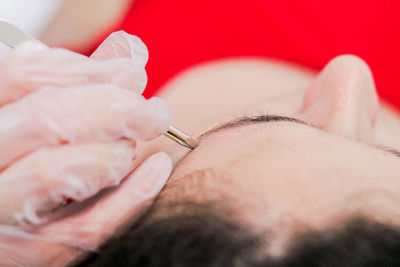 Cropped hand of beautician using tool on female customer