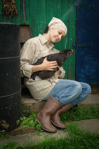 Woman sitting with chicken by door