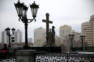 Statue of street light in city against sky