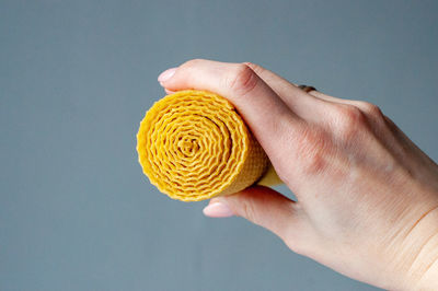 Close-up of hand holding yellow over white background