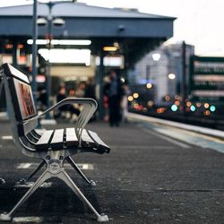 Empty bench on railroad station platform at dusk