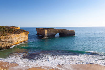 Rock formation in sea against clear sky