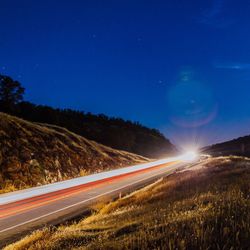 Light trails on road against sky at night