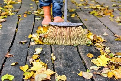 Low section of person sweeping on boardwalk