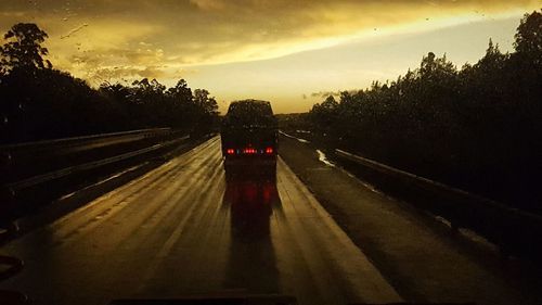 Cars on road against sky during sunset