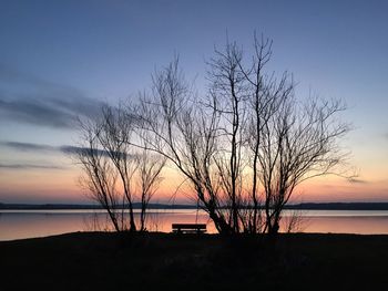 Silhouette bare tree by lake against sky during sunset