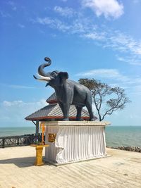 Statue by sea against sky