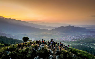 People on mountain against sky during sunset