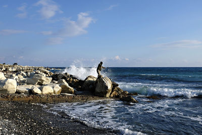 Fisherman fishing at sea shore against sky