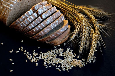 Close-up of wheat and brown breads over black background