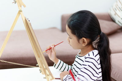 Close-up of girl painting on easel