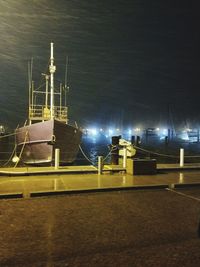 Illuminated boats moored in sea against sky at night