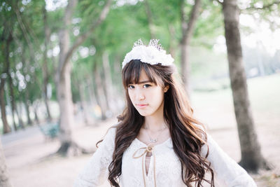 Portrait of woman wearing tiara while standing against trees