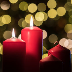 Close-up of illuminated candles against christmas lights