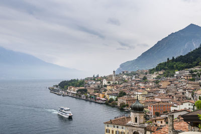 Residential district by lake and mountains against cloudy sky